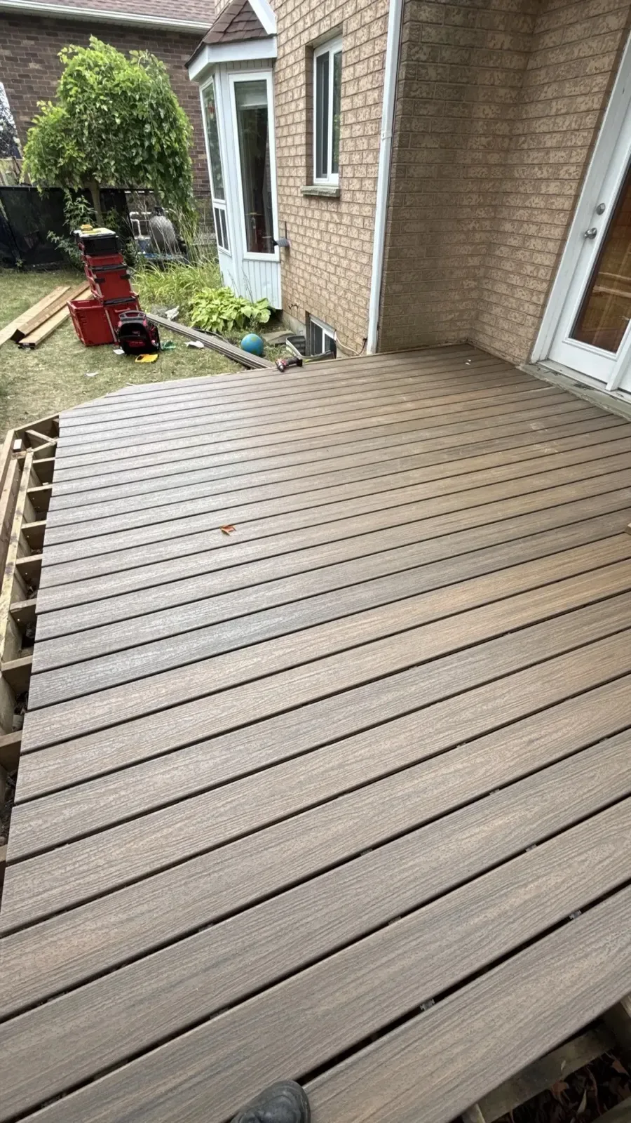 Brown composite deck boards beside a house and an open yard