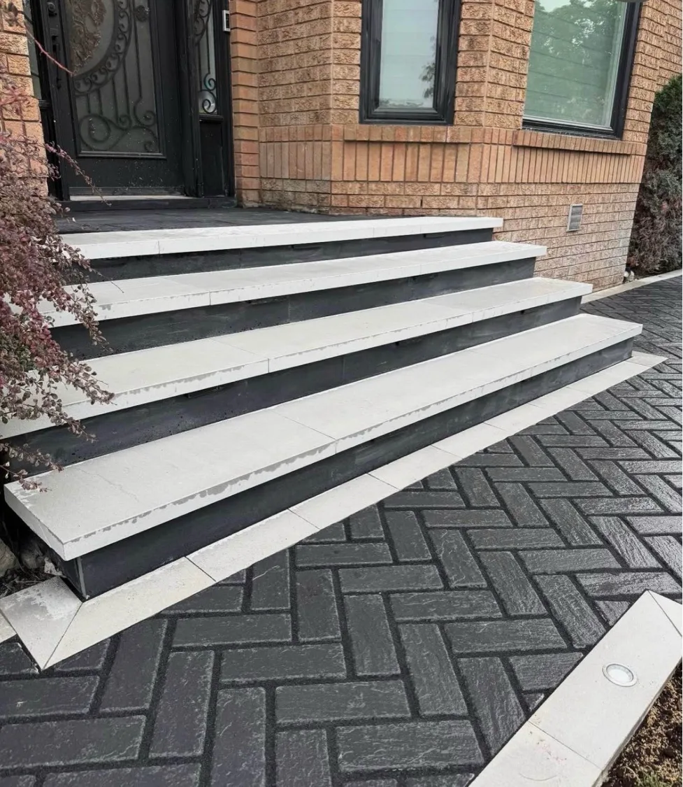 Light grey slab step entry with charcoal risers leading to red brick home with charcoal herringbone driveway — D&D Exterior Finishing Waterloo