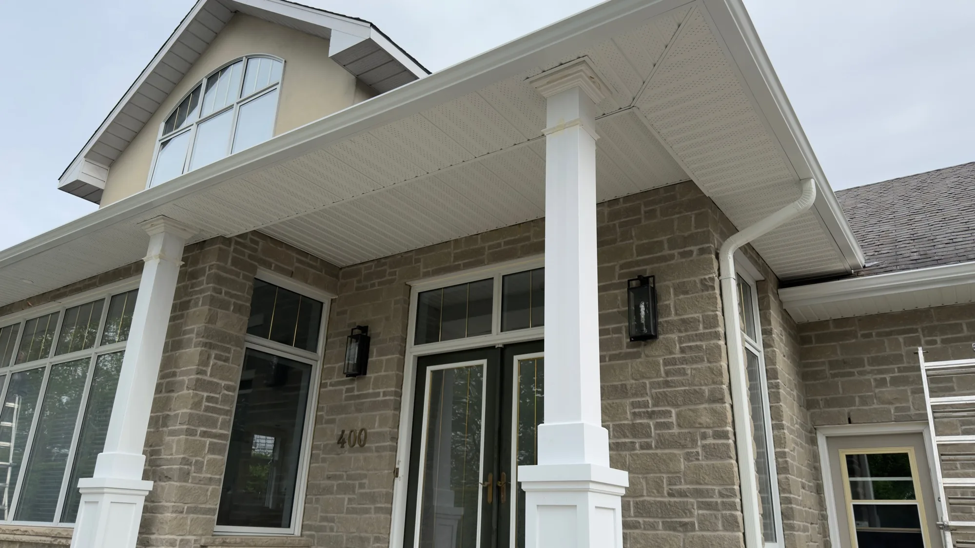 White vented soffit installation on stone home with columns β D&D Exterior Finishing Kitchener-Waterloo